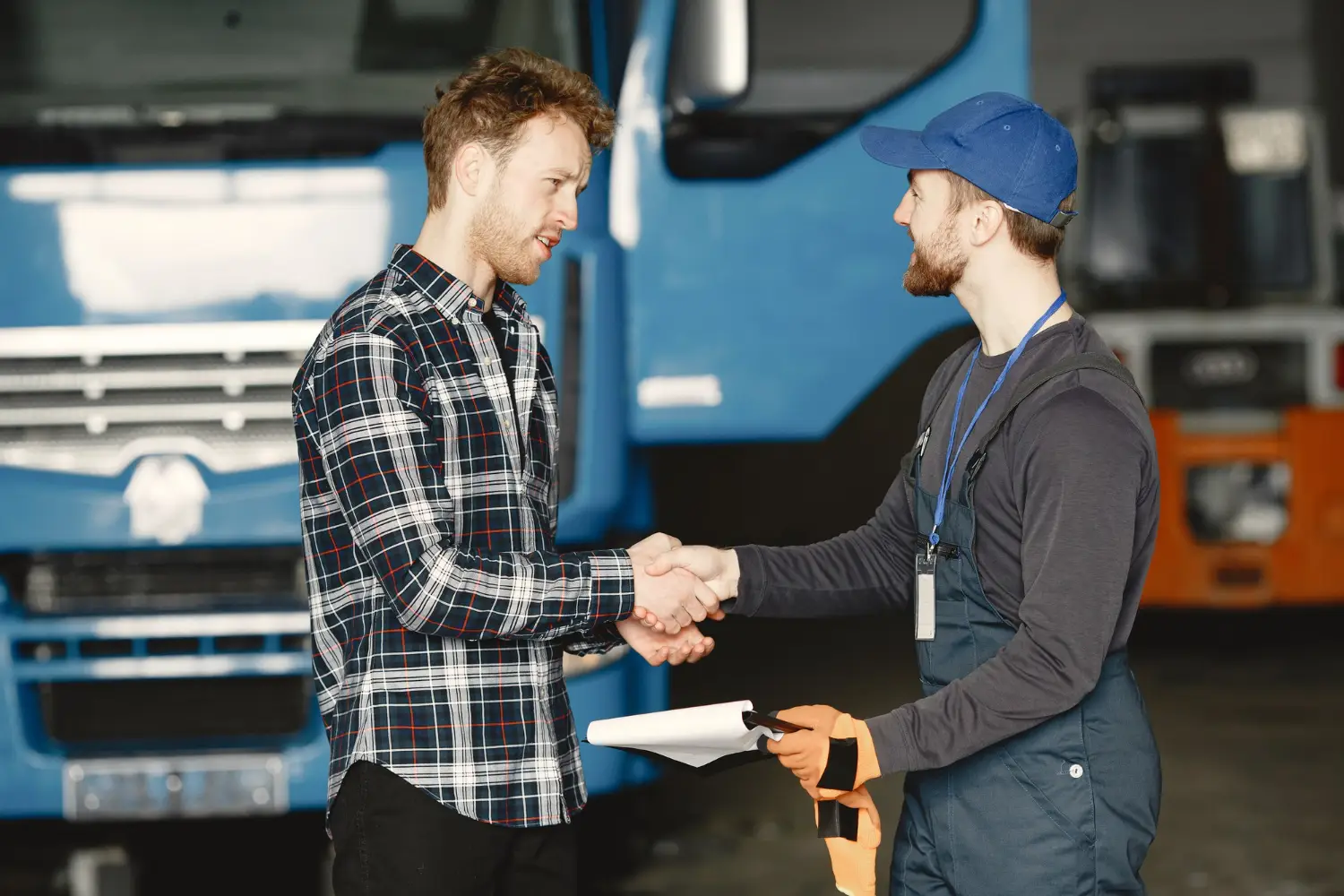 Truck driver handshaking with a salesman after completing the equipment financing process